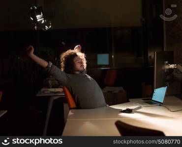 Young man working on computer at night in dark office. The designer works in the later time.