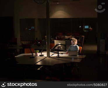 Young man working on computer at night in dark office. The designer works in the later time.