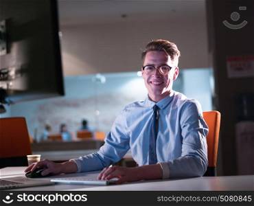 Young man working on computer at night in dark office. The designer works in the later time.
