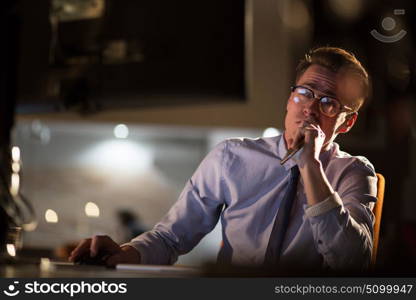 Young man working on computer at night in dark office. The designer works in the later time.