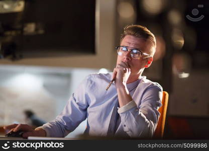 Young man working on computer at night in dark office. The designer works in the later time.