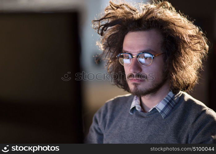 Young man working on computer at night in dark office. The designer works in the later time.