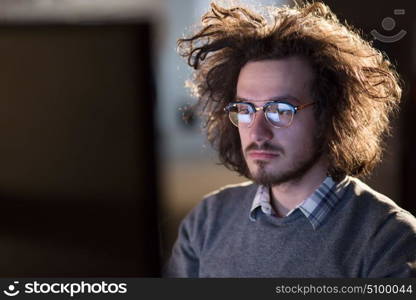 Young man working on computer at night in dark office. The designer works in the later time.