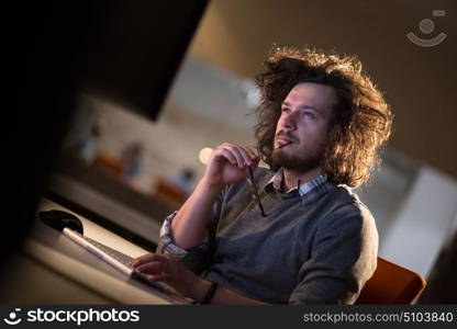 Young man working on computer at night in dark office. The designer works in the later time.