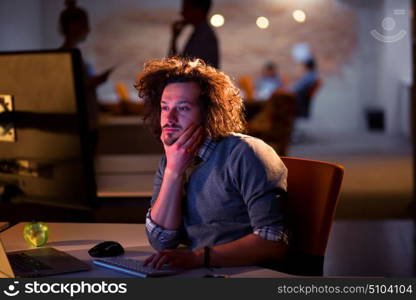 Young man working on computer at night in dark office. The designer works in the later time.