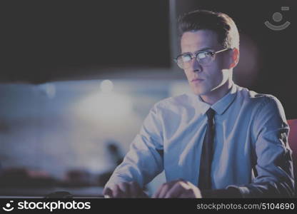 Young man working on computer at night in dark office. The designer works in the later time.