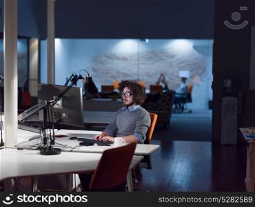 Young man working on computer at night in dark startup office. The designer works in the later time.