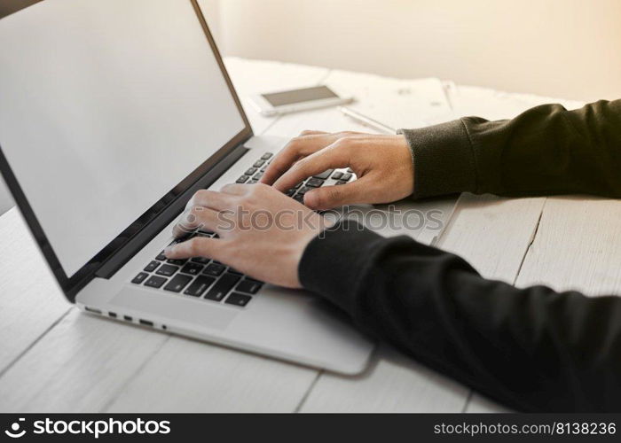 Young man working on his laptop with blank copy space screen for your advertising text message in office, sitting at the wooden desk  