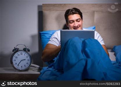 Young man working on laptop in bed