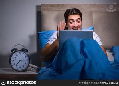 Young man working on laptop in bed