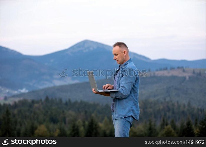 young man working on laptop in the mountains. working online. Cellular network broaband coverage concept.. young man working on laptop in the mountains. working online. Cellular network broaband coverage concept
