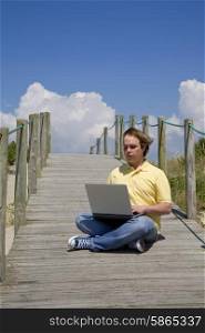 young man working with computer at the beach