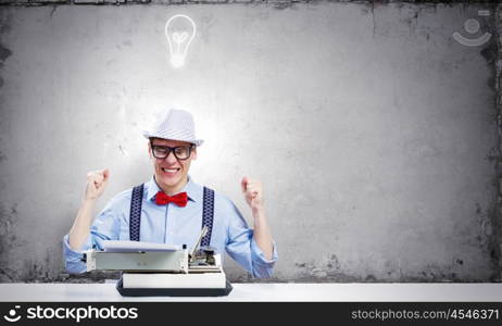 Young man writer. Young funny man in glasses writing on typewriter