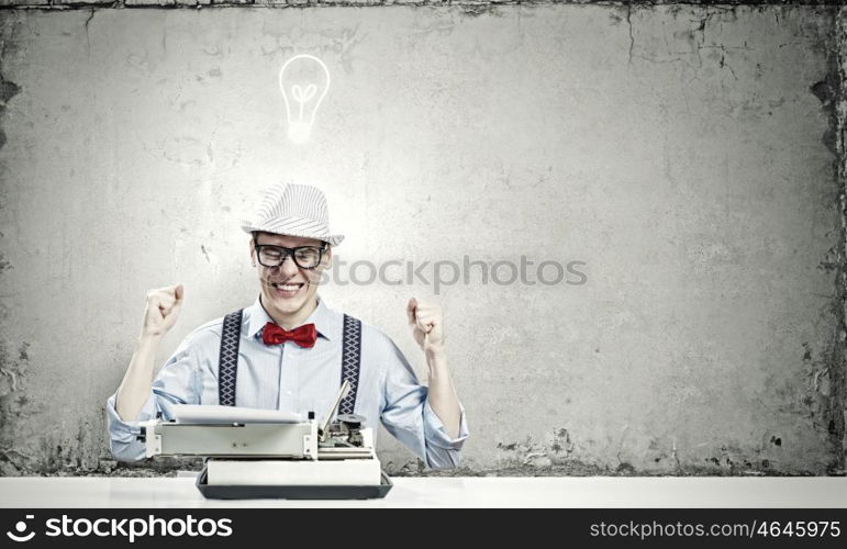 Young man writer. Young funny man in glasses writing on typewriter