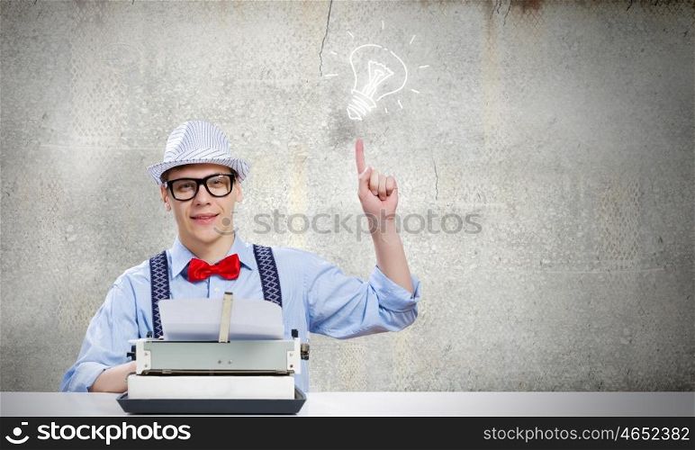 Young man writer. Young funny man in glasses writing on typewriter