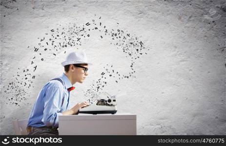 Young man writer. Young funny man in glasses writing on typewriter