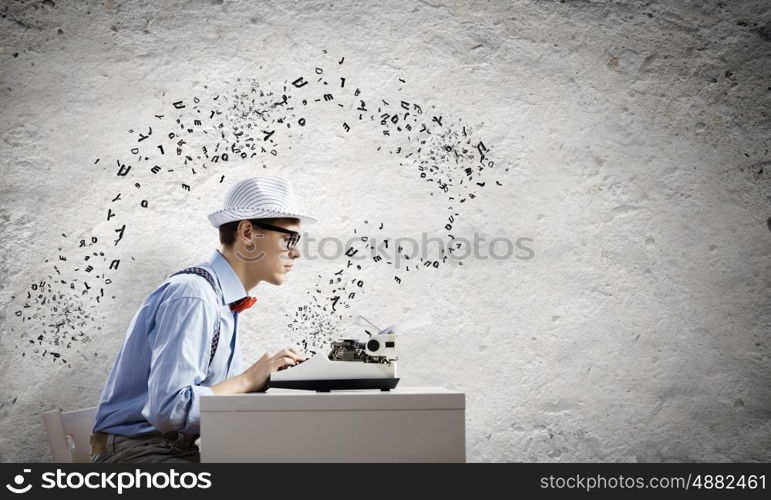 Young man writer. Young funny man in glasses writing on typewriter