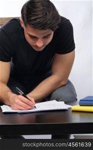 young man writing. a young man with black tshirt writing in a story board cheat