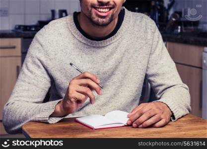 Young man writing notes in kitchen