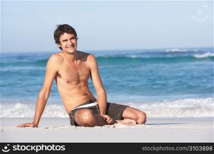 Young ManWearing Swimwear Sitting On Sandy Beach