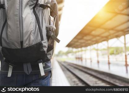 young manwith backpack standing on platform at train station - travel concept