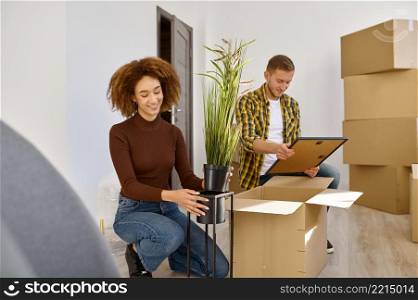 Young married couple arranging their new apartment. Wife and husband unpacking stuff. Young married couple arranging their new apartment