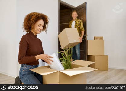 Young married couple arranging their new apartment. Wife and husband unpacking stuff. Young married couple arranging their new apartment