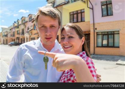 young married couple showing keys from new house. focus on the key