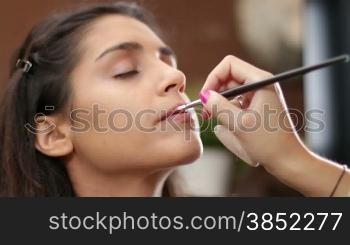Young Mediterranean girl applying make up.Beautiful woman putting cosmetics.Gorgeous fashion and beauty care close up.Cosmetician making a beauty treatment to an elegance young girl closeups.