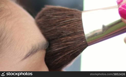 Young Mediterranean girl applying make up.Beautiful woman putting cosmetics.Gorgeous fashion and beauty care close up.Cosmetician making a beauty treatment to an elegance young girl closeups.