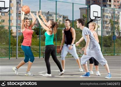 Young men and women playing basketball in a park