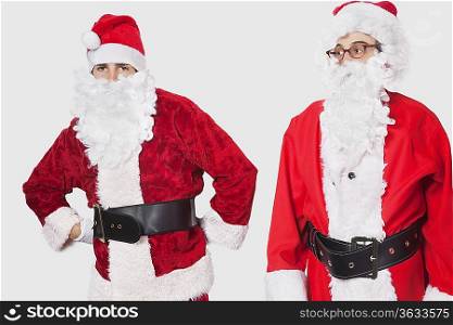 Young men in Santa costume standing against gray background