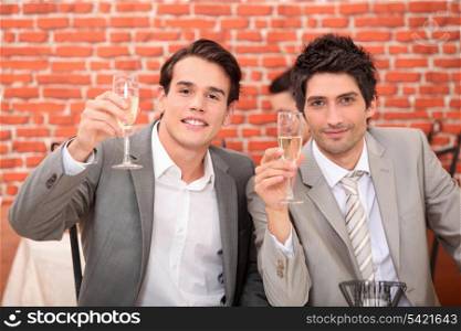Young men in suits drinking champagne