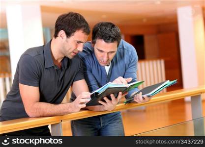 Young men looking at agenda in building hall