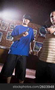 Young men looking at cellular phone while at billiard hall