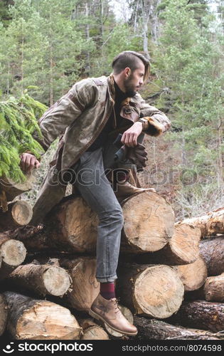 Young men on logs in the forest. Leather and jeans. Outdoor fashion