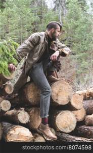 Young men on logs in the forest. Leather and jeans. Outdoor fashion