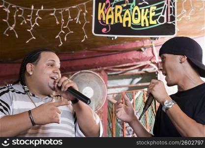 Young men singing at local bar, night