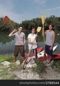 Young men with friends near river, discussing how to paddle in a kayak