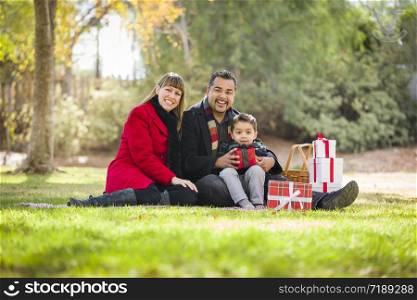 Young Mixed Race Family Enjoying Christmas Gifts in the Park Together.