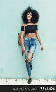Young mixed woman with afro hair standing on the street. Young mixed woman with afro hair standing on the street. Female wearing casual clothes in urban background. Lifestyle concept