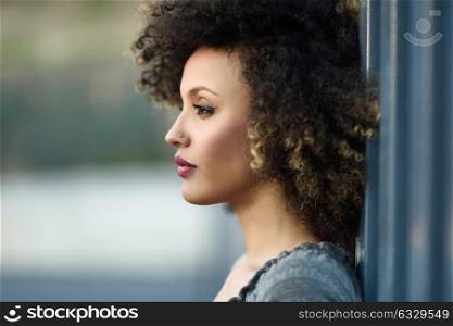 Young mixed woman with afro hairstyle standing in urban background. Black girl wearing casual clothes.