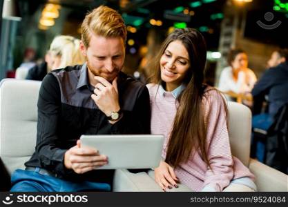 Young modern couple sitting together and using a tablet