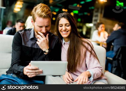 Young modern couple sitting together and using a tablet