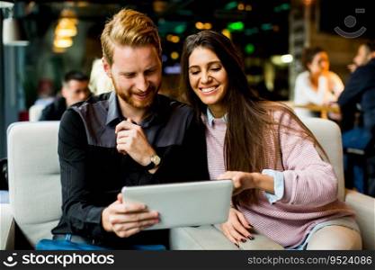 Young modern couple sitting together and using a tablet