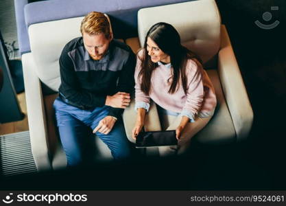 Young modern couple sitting together and using a tablet, View from above