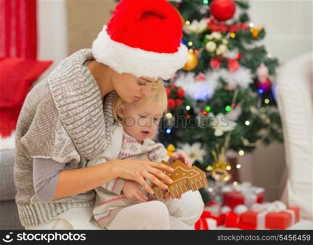 Young mom and baby girl playing near Christmas tree