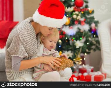 Young mom and baby girl playing near Christmas tree