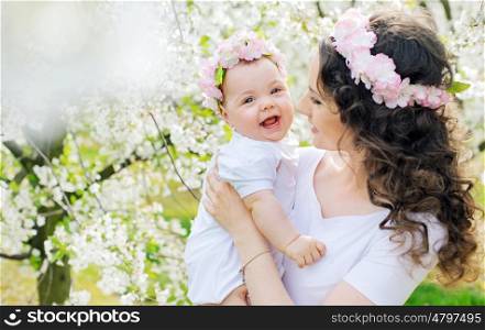 Young mom and her little baby relaxing in a spring orchard