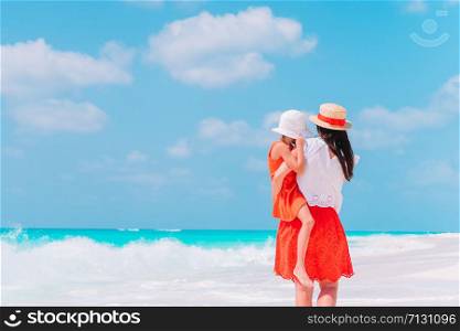 Young mom and her little daughter have fun on the beach. Beautiful mother and daughter on Caribbean beach